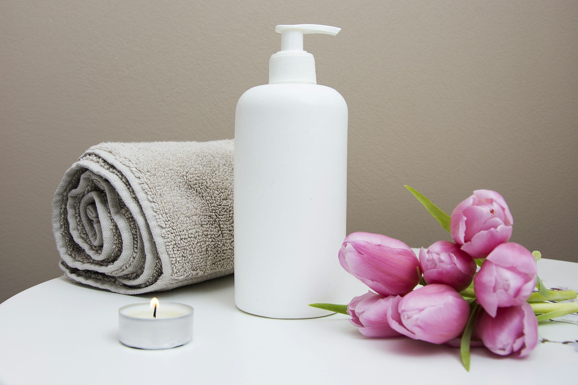 Studio details: a white pump bottle, a rolled grey towel and pink tulips
